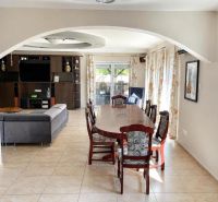 Dining table and sofa in a bright interior of a family house with tiles.