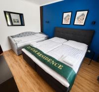 A bedroom in a family house with a wooden decor floor and a dark blue wall.