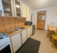A kitchen in a 2-room apartment with a dining table, ceramic tiles, and a kitchen unit.