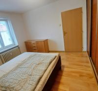 Bedroom with a bed, dresser, and wooden decor flooring in a two-room apartment.