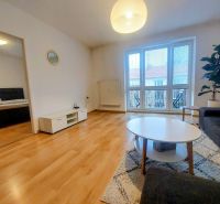Living room of a two-room apartment with a wooden decor floor and spacious windows.