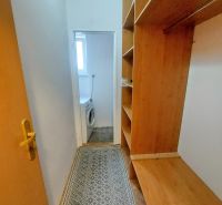 A narrow hallway with built-in wardrobes and a view of the washing machine in a 2-room apartment.