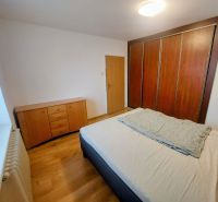 A bedroom with a bed, a large wardrobe, and a floor with a wooden decor in a 2-room apartment.