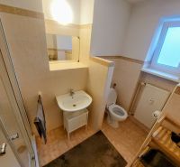 Bathroom of a 2-room apartment with tiles, a shower, a sink, and a window.