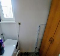 Washing machine next to the cabinet in the bathroom of a two-room apartment with dim lighting.