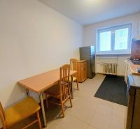 A kitchen in a 2-room apartment with a dining table and chairs made of wood.