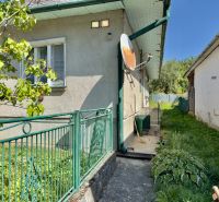 A family house in Lipany with a green fence, a satellite dish, and a garden plant.