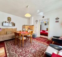 A dining room with a patterned carpet and wooden furniture in a family house.