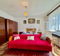 A bedroom with carpets, a red sofa, and retro furniture in a family house.