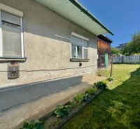 A family house in Lipany with a garden, flower bed, grassy yard, sunny day.