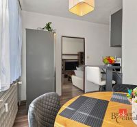 Dining area in a 2-room apartment with a table and chairs, flowers on the table.
