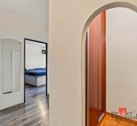 A bright bedroom with a bed, a television, and a wooden decor floor in a two-room apartment.