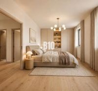 A bedroom in a family house with a wood-patterned floor, a soft carpet, and natural color scheme.