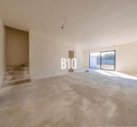 A spacious interior in a family house with bare concrete surfaces and large windows.
