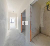 A hallway of a family house with a view of the window, unfinished walls and floors.