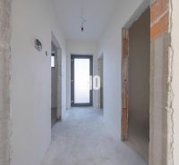 Unfurnished hallway of a family house with white walls and a cement floor.