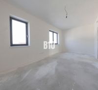 Empty room with two windows and an unfinished floor in a family house.