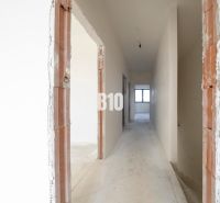 A hallway with white walls and unfinished doors in a family house.