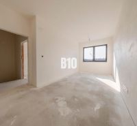 A bright room in a family house with a concrete floor and a large window.
