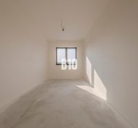Empty room with a window, white walls, concrete floor surface in a family house.