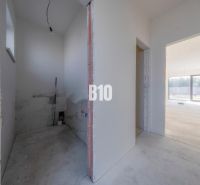 The interior of an unfinished family house with open spaces and large windows.