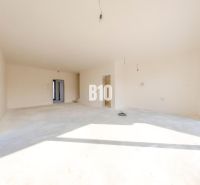 A spacious interior of a family house with large windows and white walls.