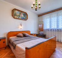 Bedroom in a family house with a bed and furniture, floor with wooden decor.