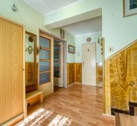 The interior of a family house with a wooden decor floor, staircase, and doors.