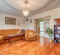 Living room in a family house with a sofa, chandelier, bookshelf, and wooden decor flooring.