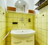 Bathroom in a family house with a sink, mirror, and yellow tiles, floor with wooden decor.