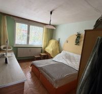 A bedroom with a bed, table, and wooden decor flooring in a 3-room apartment.