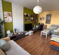 Living room with wood-patterned flooring in a 3-room apartment, cozy furniture and decorations.