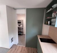 A kitchen in a cottage with a wooden decor floor and sliding doors.