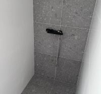 Shower corner with dark tiles in the Cottage.
