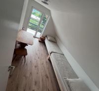 A room in a cottage with a wooden decor floor and a view of greenery.