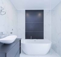 A bathroom in a family house with a freestanding bathtub and black tiles on the wall.