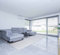 Living room with a spacious sofa and large windows in a family house.