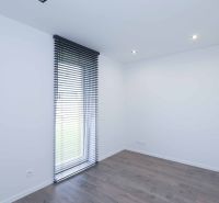 A room in a family house with a floor featuring a wooden decor and vertical blinds.