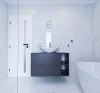 A bathroom in a family house with white tiles and a dark washbasin counter.