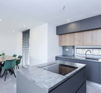 A kitchen in a family house with a kitchen unit and a dining area with green chairs.