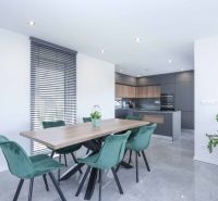 Dining room in a family house with a large table and green chairs.