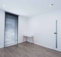 A white room with a wood-patterned floor and a table in a family house.