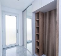 Entrance hallway in a family house with a wooden decor floor and a mirror.