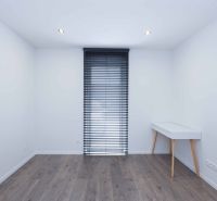 Room in a family house with a wooden decor floor and a table next to the window.