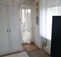 A room in a family house with white furniture, a television, and a carpet with a flower pattern.