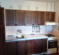 A kitchen in a family house with wooden cabinets and a tiled wall.