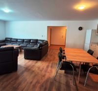Living room with a sofa, dining table, and kitchen unit in a three-room apartment.