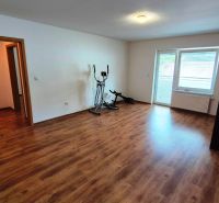 A room in a 3-room apartment, wooden decor flooring, exercise machines, open doors.