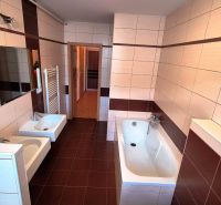 A bathroom in a 3-room apartment with a bathtub, a sink, and ceramic tiles.