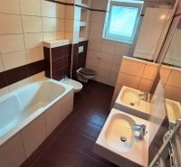 A bathroom in a 3-room apartment with two sinks, a bathtub, and modern tiles.